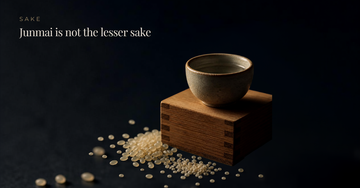 A ceramic sake cup on a cedar masu box with milled rice grains — Junmai is not the lesser sake