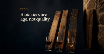 Three worn oak barrel staves lean against a stone wall, each paired with a small glass of wine showing a different hue — Rioja tiers are age, not quality