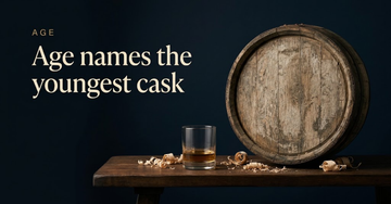 A single whisky dram beside a weathered oak cask end, grain worn and faded, curls of sawdust on a dark wooden bench — Age names the youngest cask
