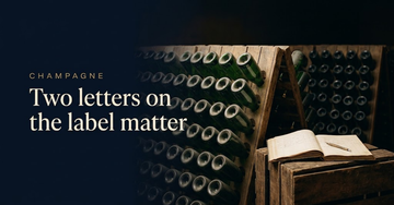Dozens of identical unlabelled Champagne bottles racked together in a cooperative cellar, a grower ledger open on a crate — Two letters on the label matter