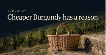 A plain wicker grape basket on a stone farmhouse step, modest vine rows climbing a gentle hillside behind — Cheaper Burgundy has a reason