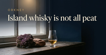 A chunk of heather and sandstone beside one whisky glass on a weathered wooden ledge, grey sea light behind — Island whisky is not all peat